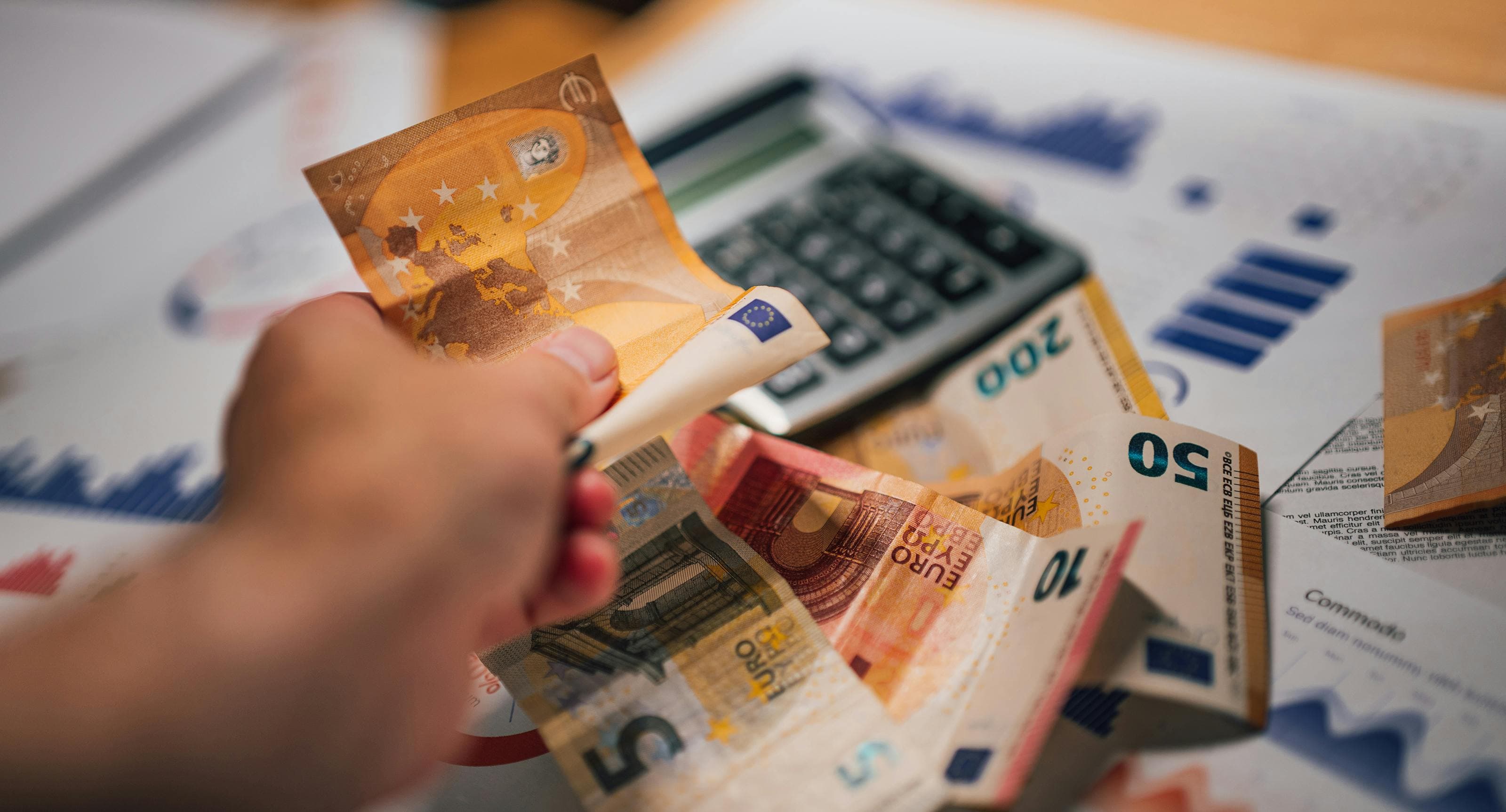 Euro banknotes, a calculator, and budget charts representing international cost-of-living planning